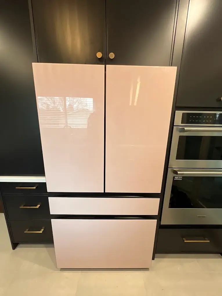 Professional technician repairing a modern black refrigerator